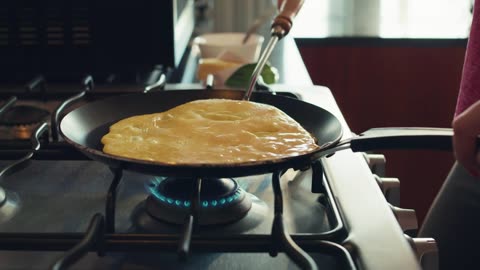 Close up shot of a woman flipping her egg omelet for breakfast.