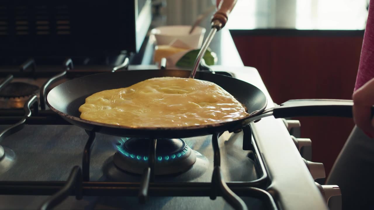 Close up shot of a woman flipping her egg omelet for breakfast.