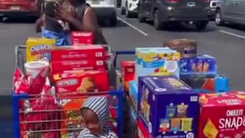 Woman has her child pose as she shows off carts full of groceries she bought using her November EBT