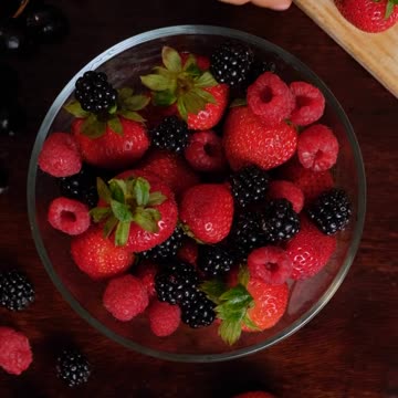 Serving strawberries, blackberries and plums in a glass bowl.