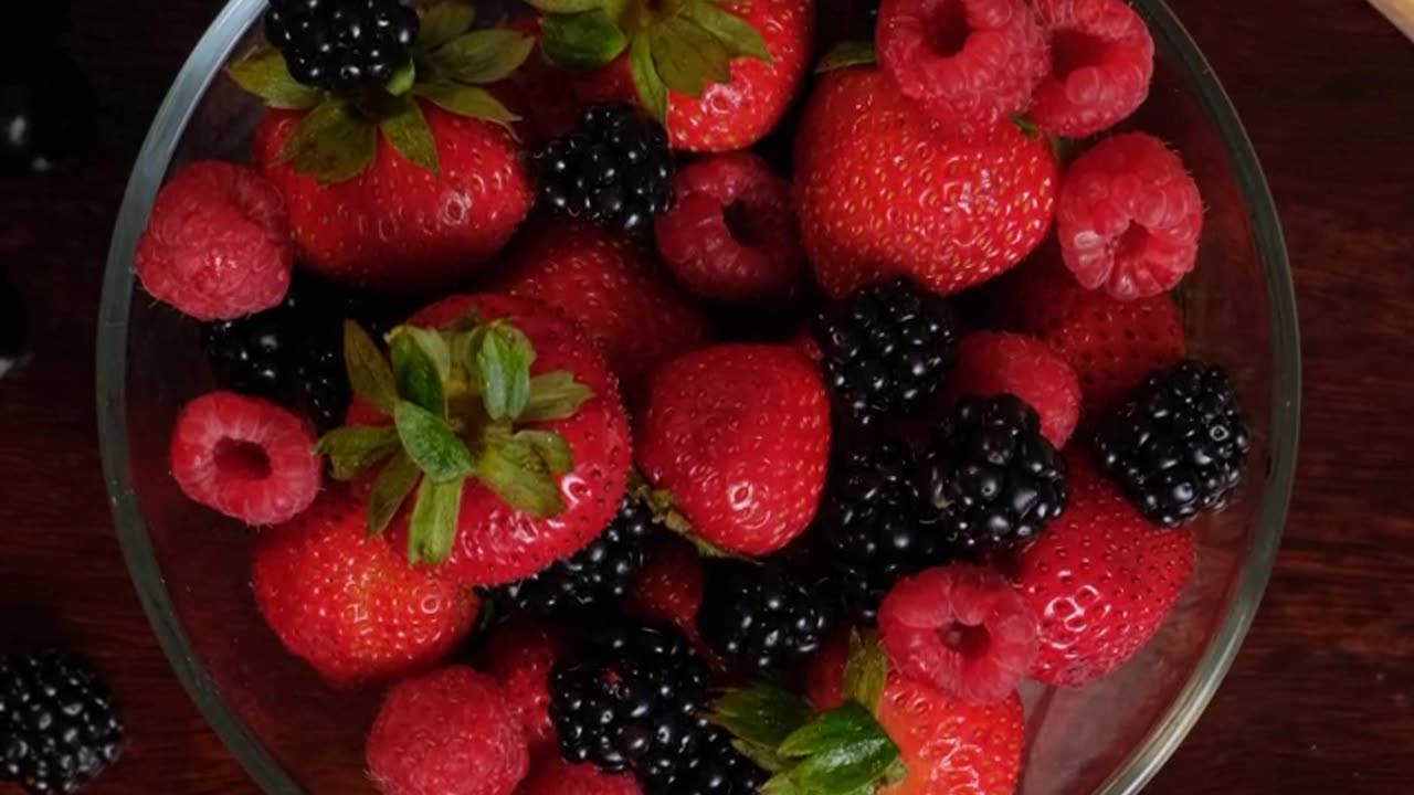 Serving strawberries, blackberries and plums in a glass bowl.