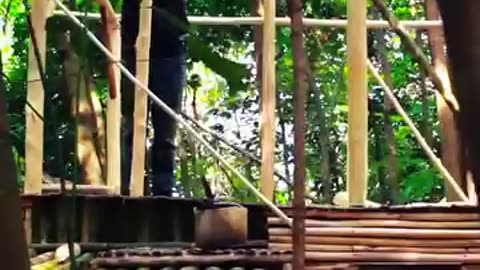 Building a two story wooden cabin with a stacked bamboo roof in the middle of the forest