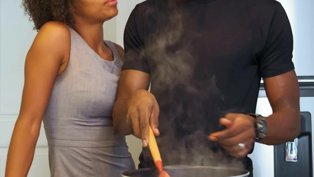 Man cooking is surprised by his wife with a hug