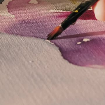 Hands painting a canvas with watercolor