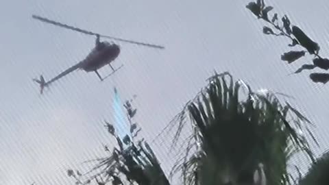 Helicóptero na Flórida Pulveriza Pesticidas Azuis para Mosquitos