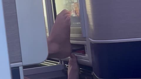Dude Using Bare Feet to Use Airplane Screen
