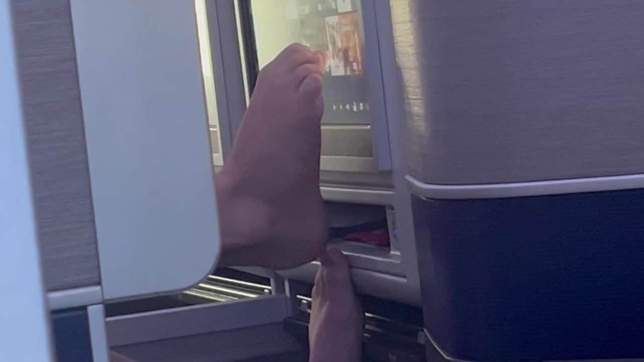 Dude Using Bare Feet to Use Airplane Screen