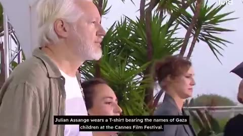 Julian Assange wears a T-SHIRT BEARING the names of GAZA CHILDREN