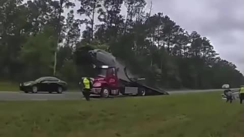 Distracted driver, jumps car over tow truck bed!!!