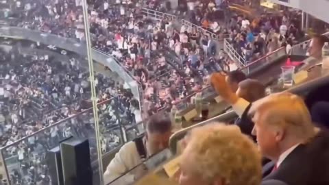 Trump dances behind bulletproof glass at a football match in New York