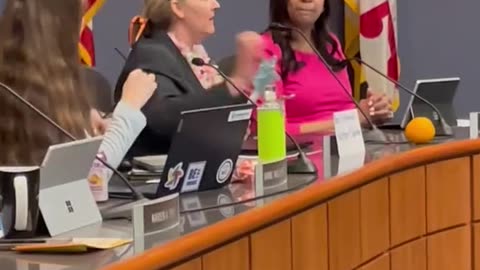 Woman identifies as school board member and is escorted out.