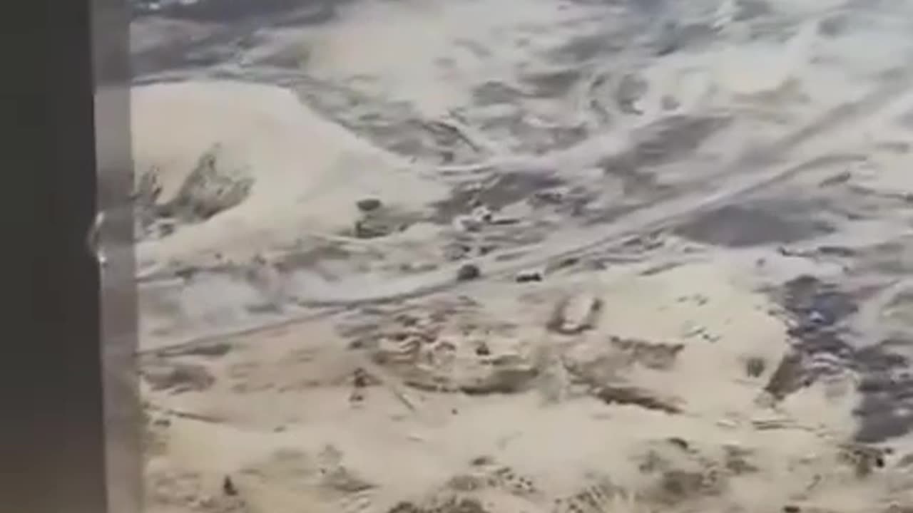 Palestinians running after an Israeli tank that is opening the way for deadly U.S. aid distribution