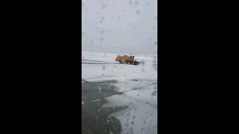 A truck is clearing the snow-covered road to allow the plane to pass