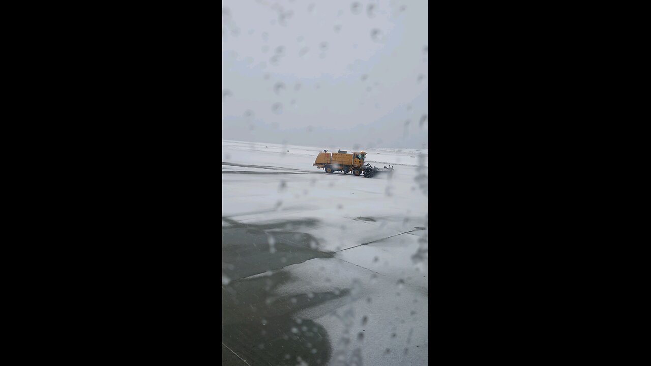 A truck is clearing the snow-covered road to allow the plane to pass