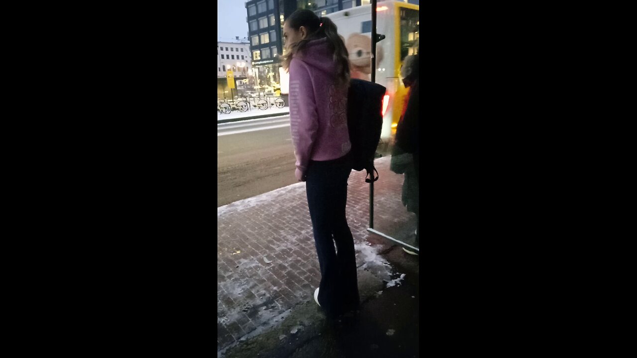 Young beautiful girl is freezing while waiting for the bus. Severe frost, she wore a light Hoodie.
