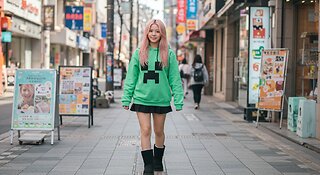A East Asian girl With a MineCraft Creeper Hoodie and black Mini Skirt also with ugg boot walking
