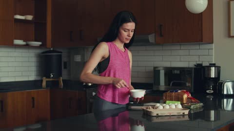 Woman preparing her morning lunch by beating eggs in her kitchen at home.