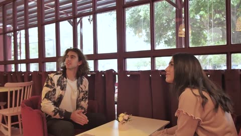 A boy and a girl holding hands, entering and having a table in a romantic.