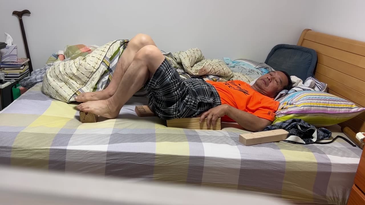 Luodong Massages Himself With 2x4's At Home On The Bed