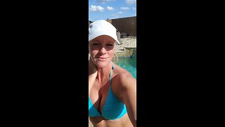 Lovely blonde in bikini top and hat by the pool