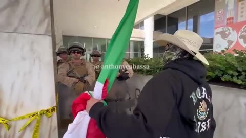 Protestor with a Mexican flag shouts at US Marines at the federal building.