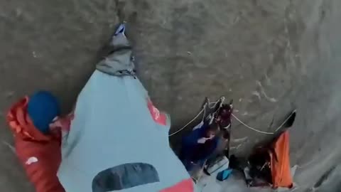 Mountain climbers sleep while suspended to a rock wall