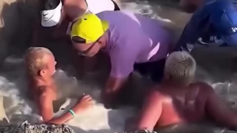 Two kids get trapped in the sand after water entered a hole they dug...