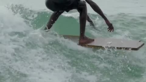 He surfing with a piece of wood