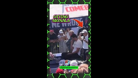 2 guys standing behind Charlie Kirk giving hand signals to shooter