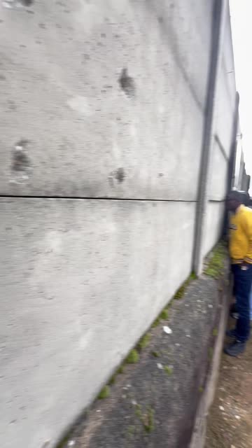 Football Fans Watch Game Through Holes In Concrete Wall