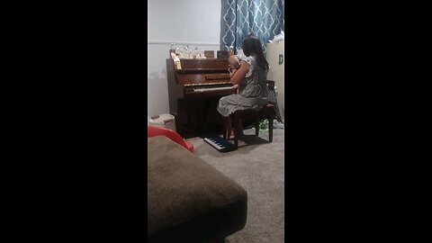 Rebekah playing piano while holding a baby