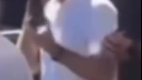 2 people behind Charlie Kirk give hand signals
