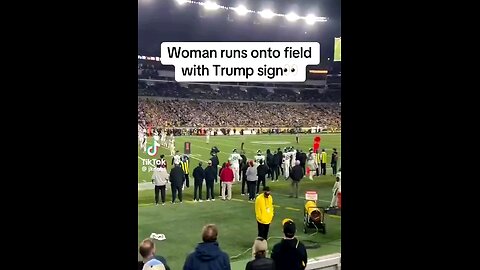 woman run onto football field with Trump sign