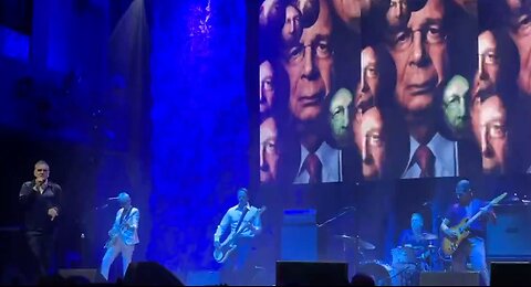 Morrissey displays images of Klaus Schwab, Anthony Fauci and Bill Gates as he sang about ‘criminals’