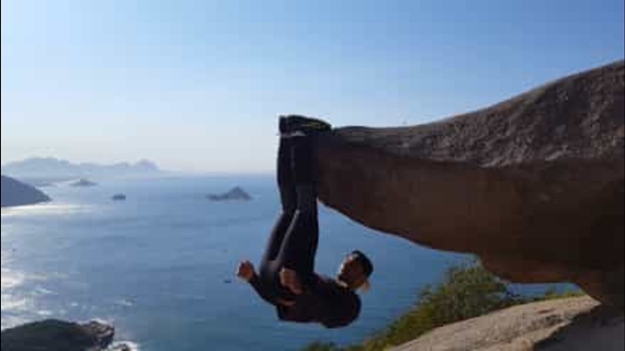 Pojke hänger med fötterna från en klippa i Brasilien