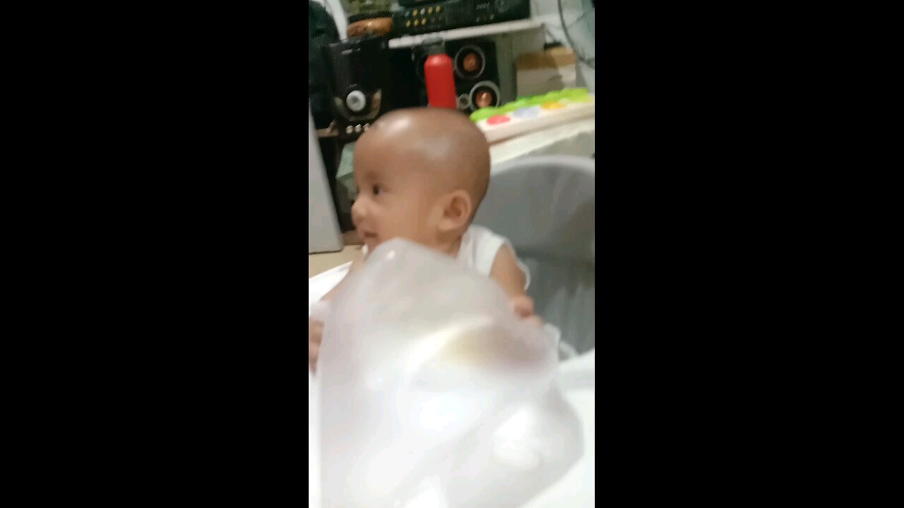 cute baby laughs at plastic waving in the air