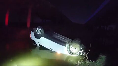 Police officers rescue a woman who was trapped in a car that had been driven off a bridge