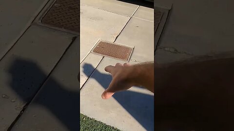 Plumbing cleanout settlement in driveway causing cracks and trip hazards.