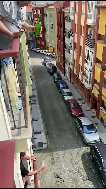 Man in Italy pours a drink for his neighbor two floors below
