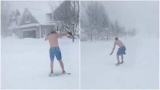Kille som surfar på snö iklädd badbyxor