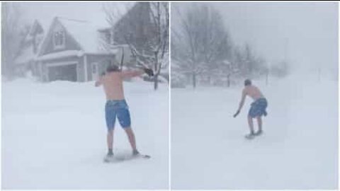 Kille som surfar på snö iklädd badbyxor