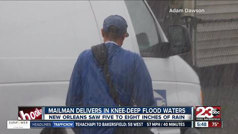 Mailman treads through knee deep water to deliver mail