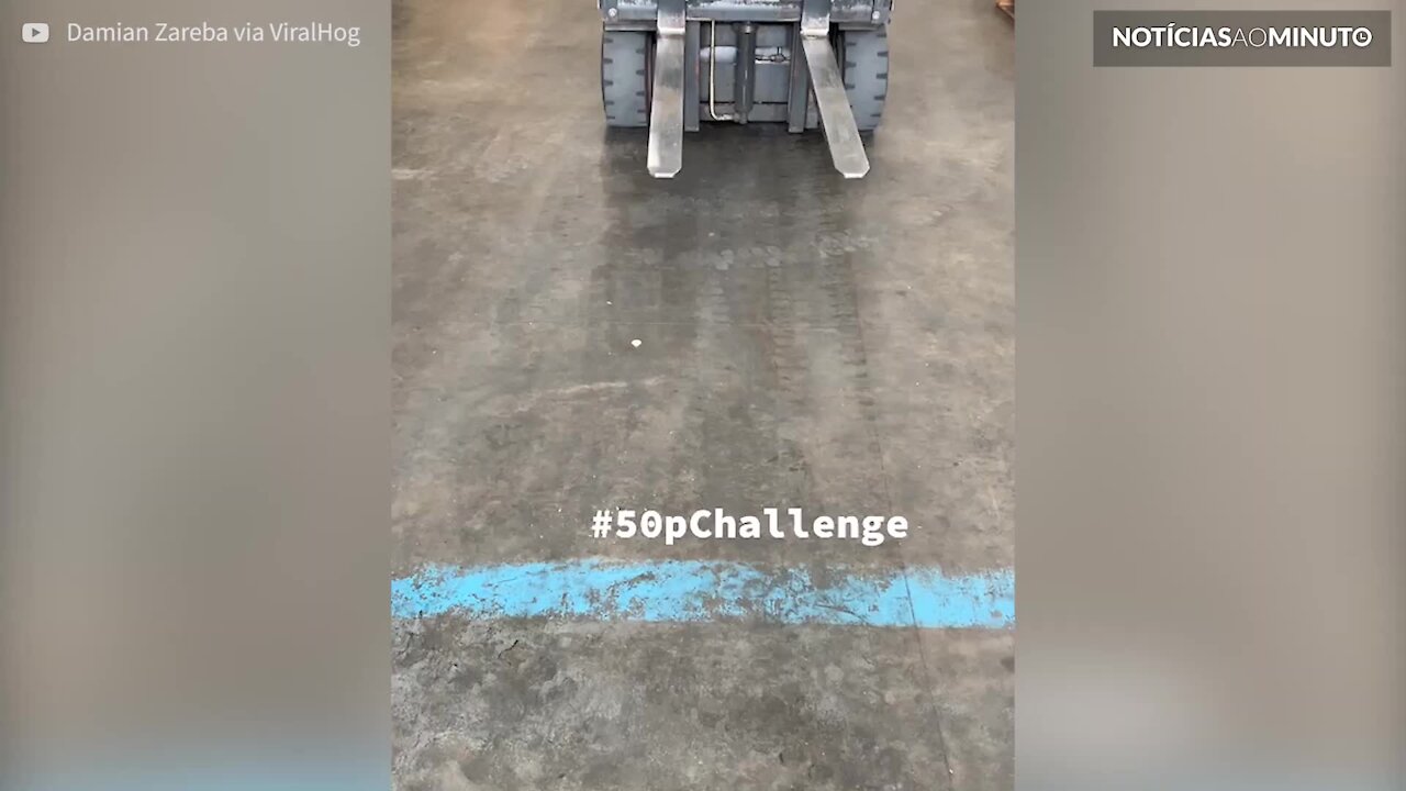 Senhor apanha moeda de 50 pence com uma empilhadora