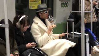 Stylish guy on Chinese metro drinks tea from wine glass