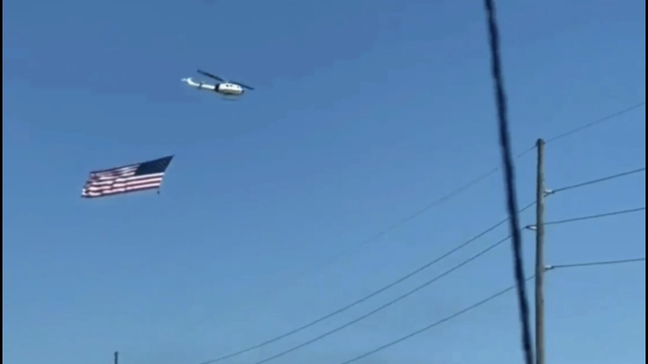 HELICOPTER FLYING ENORMOUS AMERICAN FLAG SUPPORTING THE PEOPLES CONVOY