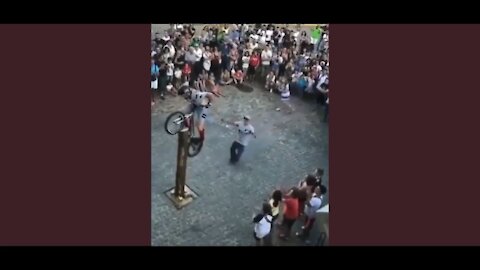 Man plants rear wheel of bicycle on tall standing log