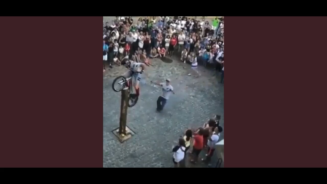 Man plants rear wheel of bicycle on tall standing log