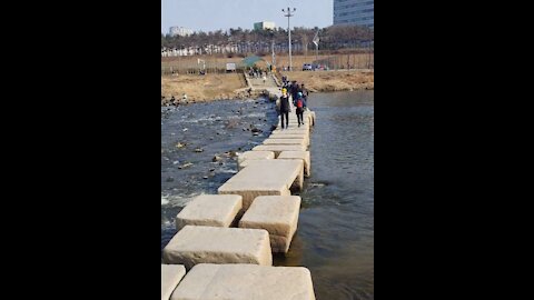 On a warm winter day, people crossing the river