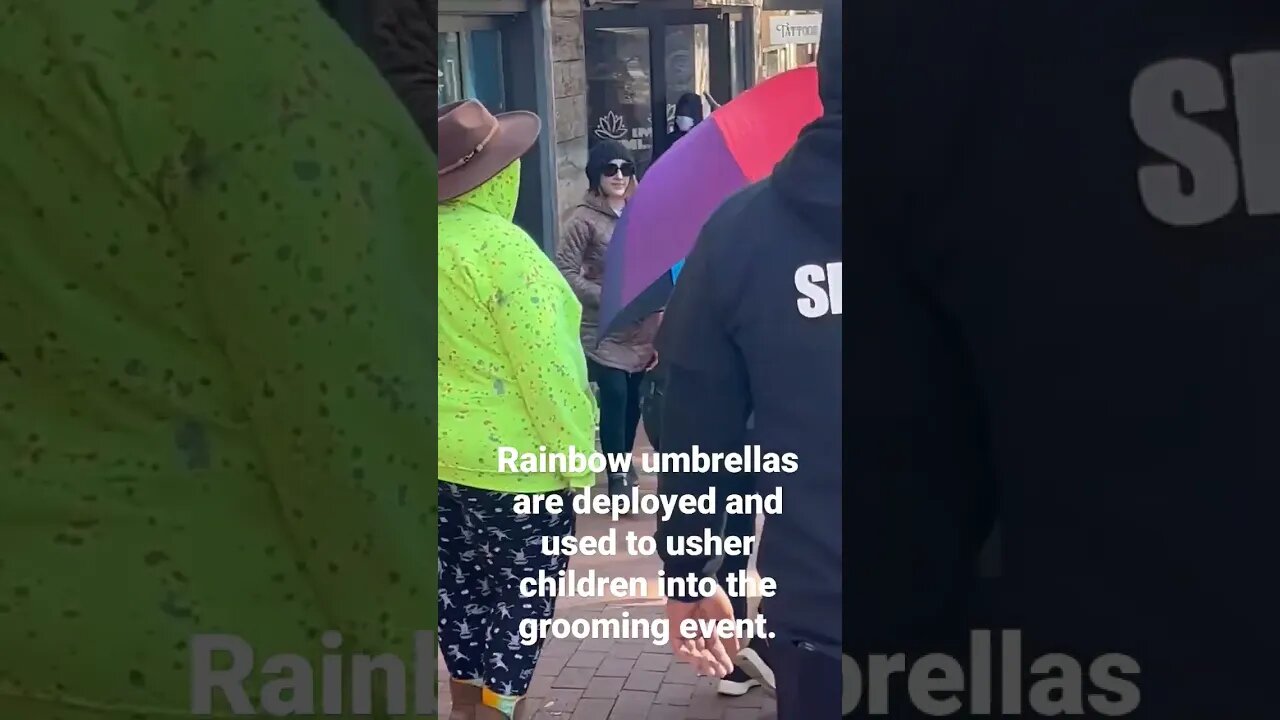 Rainbow umbrellas are deployed and used to usher children into the grooming event.