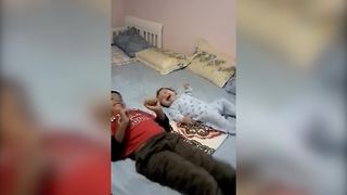 "A Young Boy And Baby Kick On Bed"